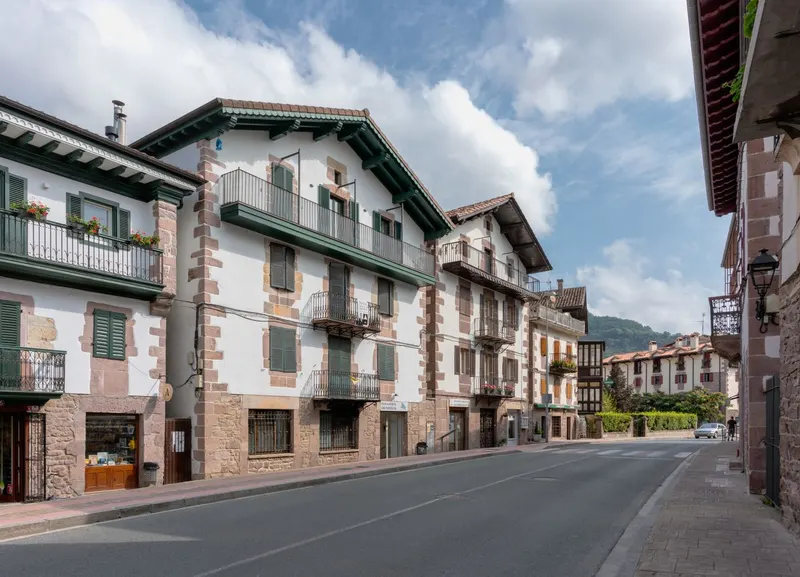Calle de un pueblo con casas de piedra y balcones de madera.